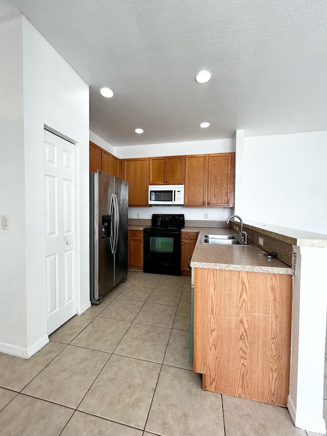 kitchen with black range with electric stovetop, sink, stainless steel fridge, a textured ceiling, and light tile patterned floors