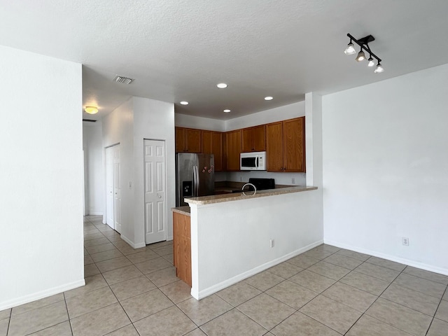 kitchen with stainless steel fridge, kitchen peninsula, and light tile patterned floors