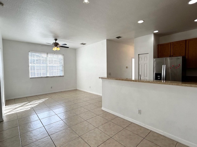 kitchen with stainless steel fridge with ice dispenser, a textured ceiling, ceiling fan, and light tile patterned flooring