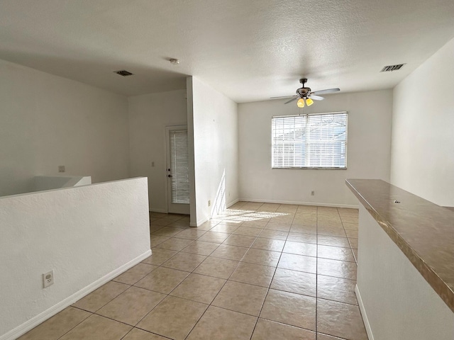 unfurnished room featuring ceiling fan, light tile patterned floors, and a textured ceiling