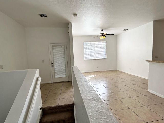 interior space featuring ceiling fan, light tile patterned flooring, and a textured ceiling