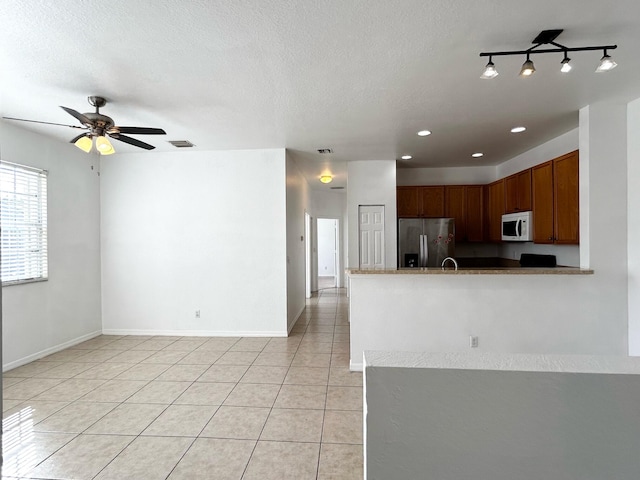 kitchen featuring stainless steel fridge, a textured ceiling, ceiling fan, and light tile patterned flooring