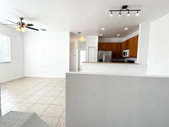 kitchen with kitchen peninsula, stainless steel refrigerator with ice dispenser, a textured ceiling, ceiling fan, and light tile patterned floors