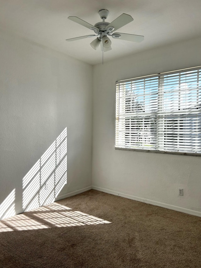 carpeted spare room featuring ceiling fan