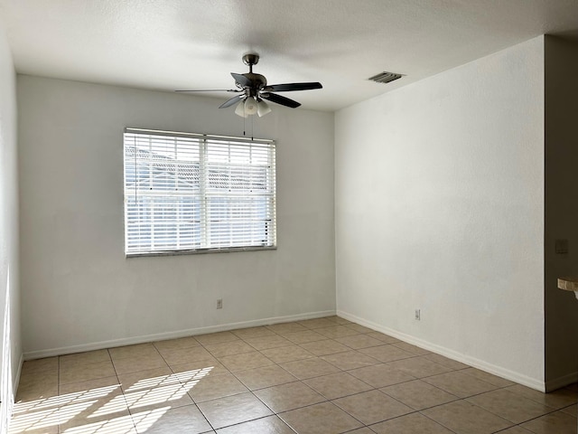 tiled spare room with a textured ceiling and ceiling fan