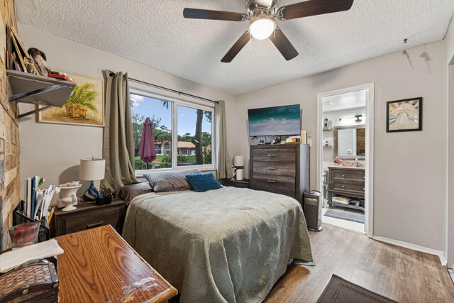 bedroom with light wood finished floors, baseboards, ensuite bath, a textured ceiling, and a ceiling fan