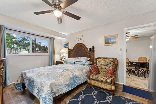 bedroom featuring baseboards, a textured ceiling, wood finished floors, and a ceiling fan