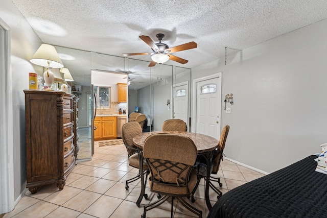 dining room featuring ceiling fan, light tile patterned floors, baseboards, and a textured ceiling