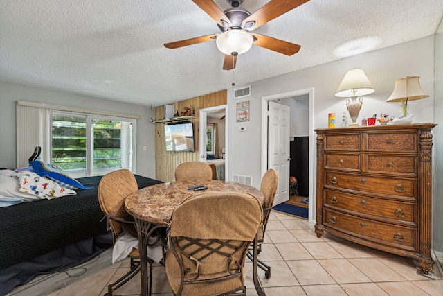 dining space with light tile patterned floors, a ceiling fan, visible vents, and a textured ceiling