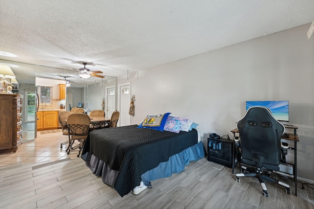 bedroom with a textured ceiling, ceiling fan, and wood finish floors