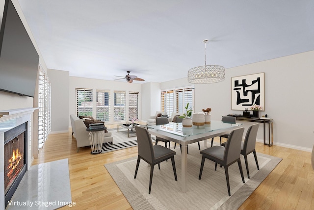 dining area featuring ceiling fan, a high end fireplace, and light wood-type flooring