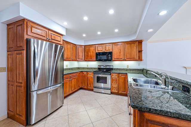 kitchen featuring sink, dark stone countertops, light tile patterned floors, kitchen peninsula, and stainless steel appliances