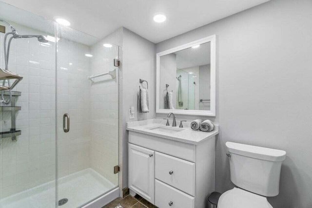 bathroom featuring vanity, a shower with shower door, and toilet