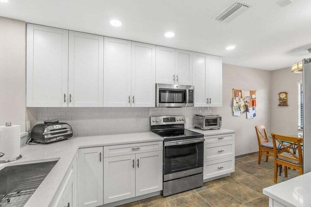 kitchen featuring white cabinets, decorative backsplash, and stainless steel appliances