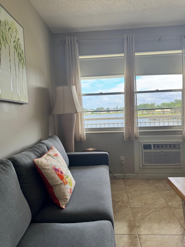 living room with a wall mounted AC, a water view, light tile patterned flooring, and a textured ceiling