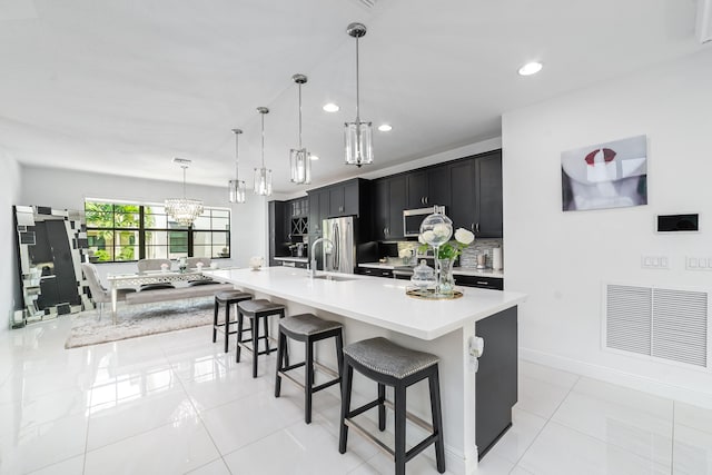 kitchen featuring pendant lighting, backsplash, appliances with stainless steel finishes, a large island, and a breakfast bar area