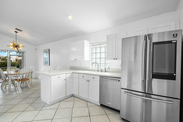 kitchen with kitchen peninsula, stainless steel appliances, vaulted ceiling, a healthy amount of sunlight, and white cabinets