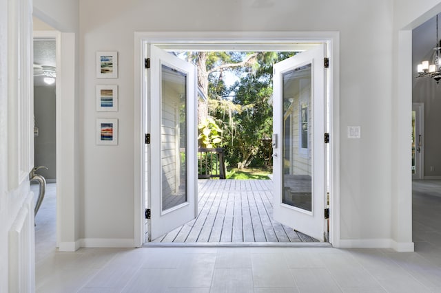 entryway with french doors, light tile patterned floors, and a notable chandelier