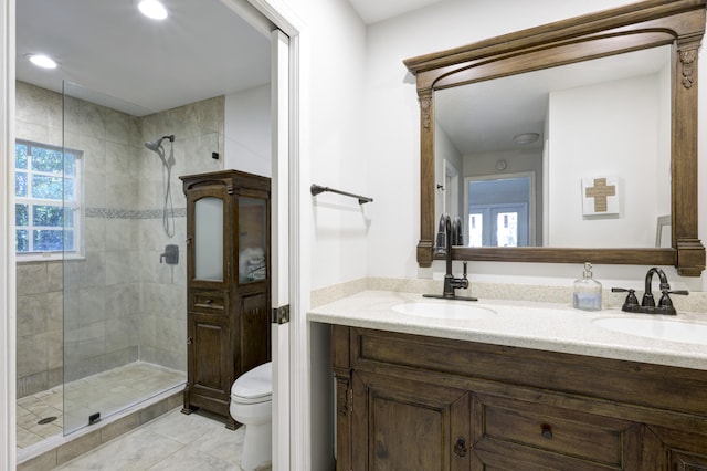 bathroom with tiled shower, vanity, toilet, and a wealth of natural light