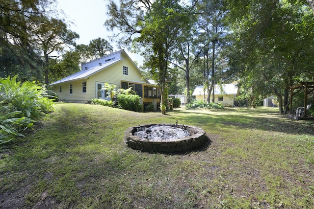 view of yard featuring an outdoor fire pit and a sunroom