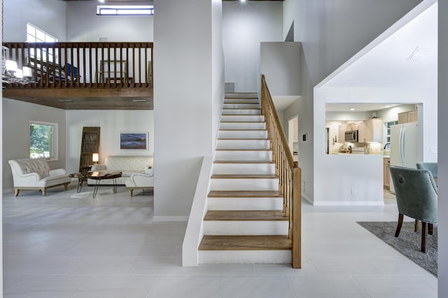 staircase with tile patterned floors and a high ceiling