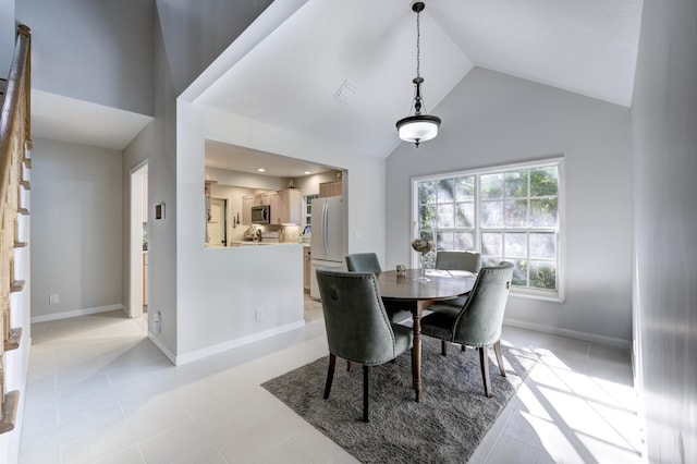 dining area with light tile patterned floors and high vaulted ceiling