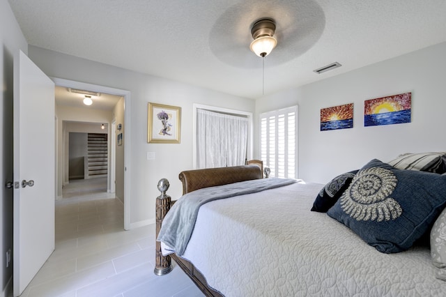 tiled bedroom featuring ceiling fan and a textured ceiling