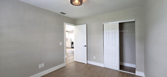 unfurnished bedroom featuring hardwood / wood-style flooring, a textured ceiling, and a closet