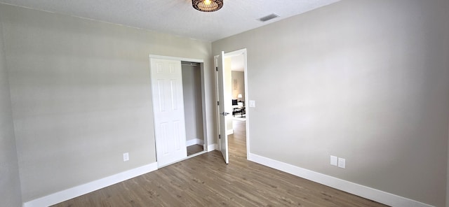 unfurnished bedroom featuring hardwood / wood-style flooring, a textured ceiling, and a closet