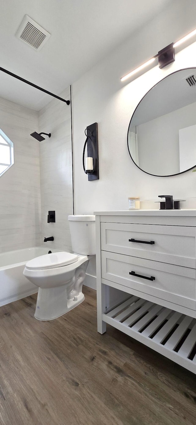 full bathroom with tiled shower / bath, toilet, vanity, and hardwood / wood-style flooring