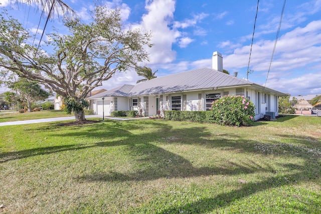 ranch-style home with central AC unit, a garage, and a front lawn