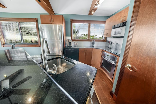 kitchen with beamed ceiling, wood-type flooring, sink, and black appliances