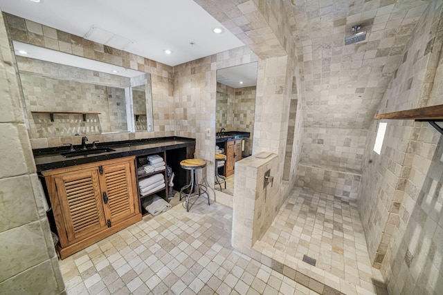 bathroom with tiled shower, vanity, and tile walls