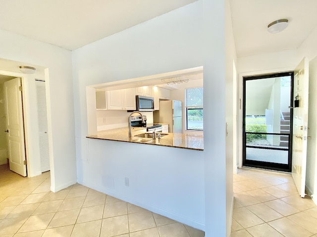 6928 Briarlake Cir Unit 104, Palm Beach Gardens, FL 33418 - kitchen featuring appliances with stainless steel finishes, light tile patterned floors, baseboards, white cabinets, and a peninsula