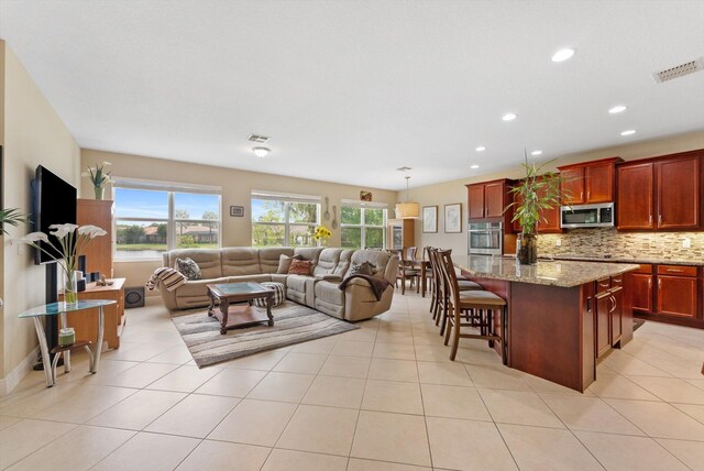 kitchen featuring sink, an island with sink, light tile patterned floors, and appliances with stainless steel finishes