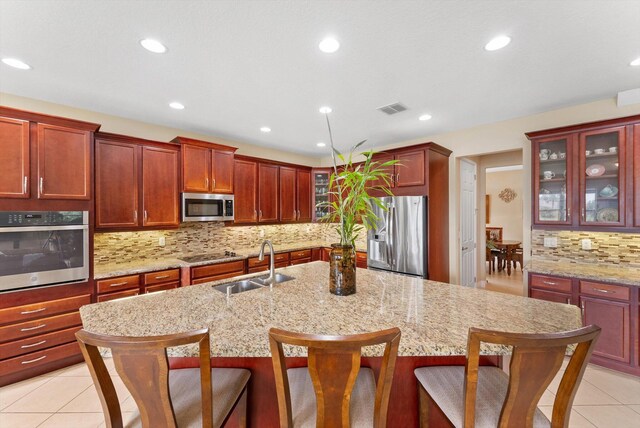 kitchen featuring backsplash, light stone countertops, light tile patterned flooring, and stainless steel appliances