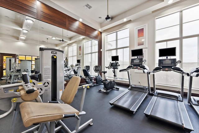 workout area featuring a tray ceiling and a high ceiling