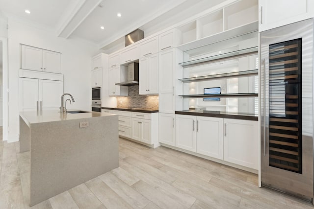 kitchen with light wood-type flooring, sink, wine cooler, and wall chimney range hood