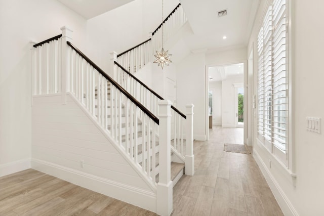 stairway featuring crown molding, hardwood / wood-style floors, and a notable chandelier