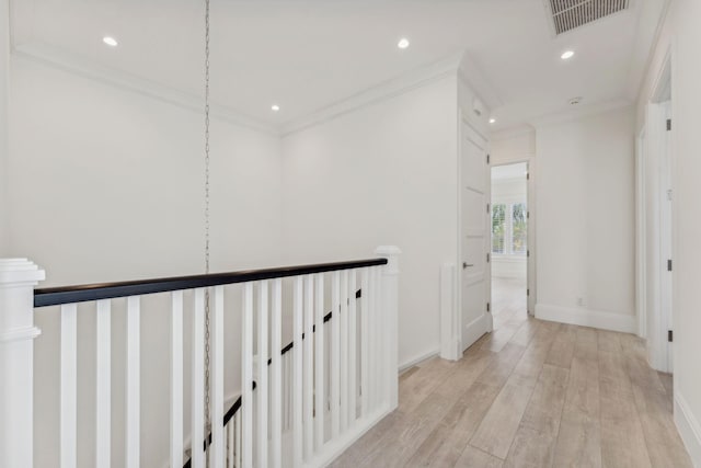 corridor with light hardwood / wood-style floors and crown molding