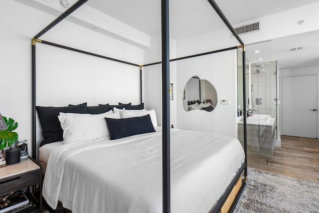 bedroom featuring ensuite bath, hardwood / wood-style floors, and sink