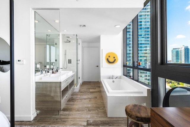 bathroom with plus walk in shower, hardwood / wood-style floors, and vanity