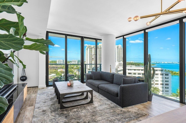 living room featuring a wealth of natural light, a water view, wood-type flooring, and a wall of windows