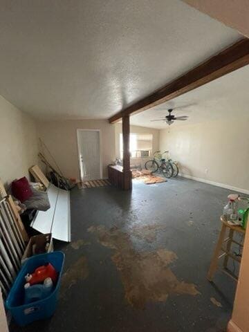 unfurnished living room featuring beamed ceiling, a textured ceiling, concrete flooring, and ceiling fan