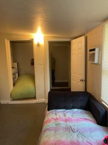 carpeted bedroom featuring a wall mounted air conditioner and a textured ceiling