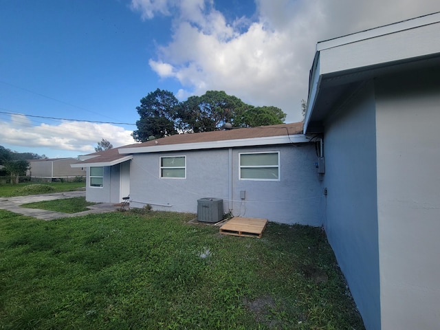 view of property exterior with a lawn and central AC unit