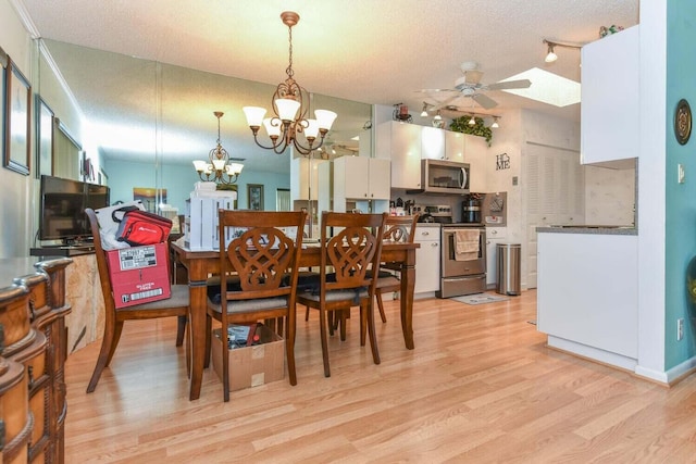 dining space featuring ceiling fan with notable chandelier, a textured ceiling, light wood-type flooring, and track lighting