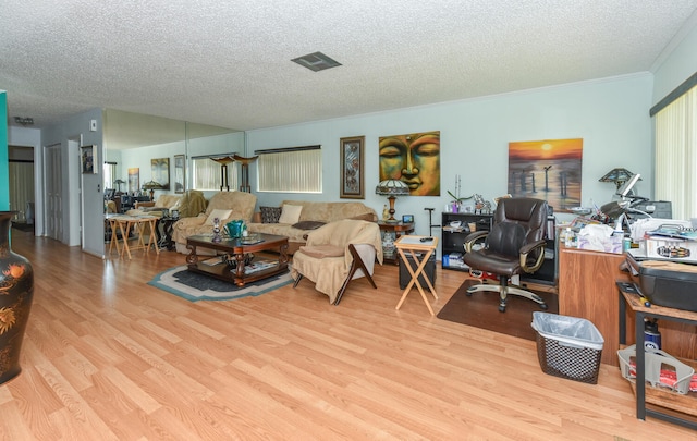 living room with ornamental molding, a textured ceiling, and light wood-type flooring