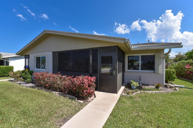 view of front of house featuring concrete block siding and a front lawn