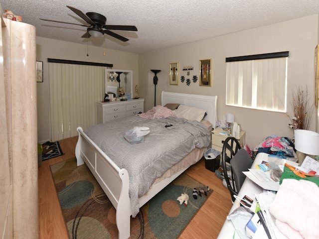 bedroom with a textured ceiling, hardwood / wood-style flooring, and ceiling fan